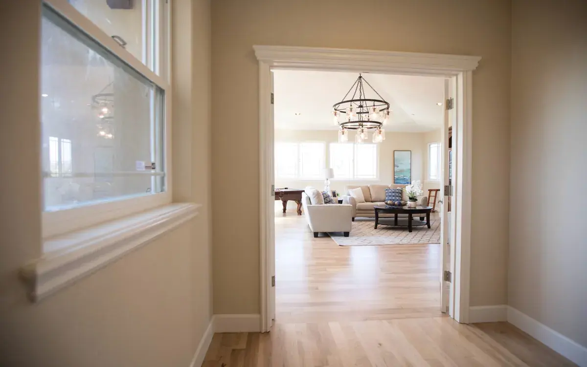 View through an open doorway into a sunlit living room with a chandelier