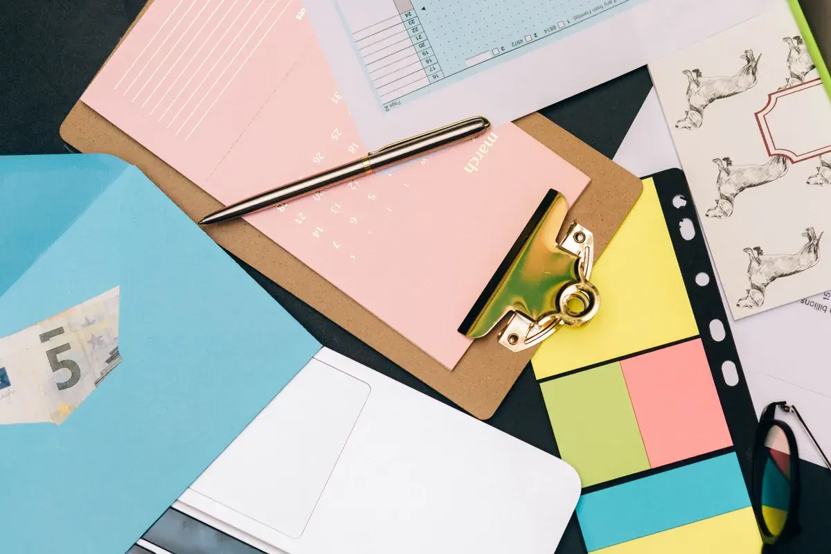 Neatly arranged desk supplies with a clipboard and colored notes on a light surface