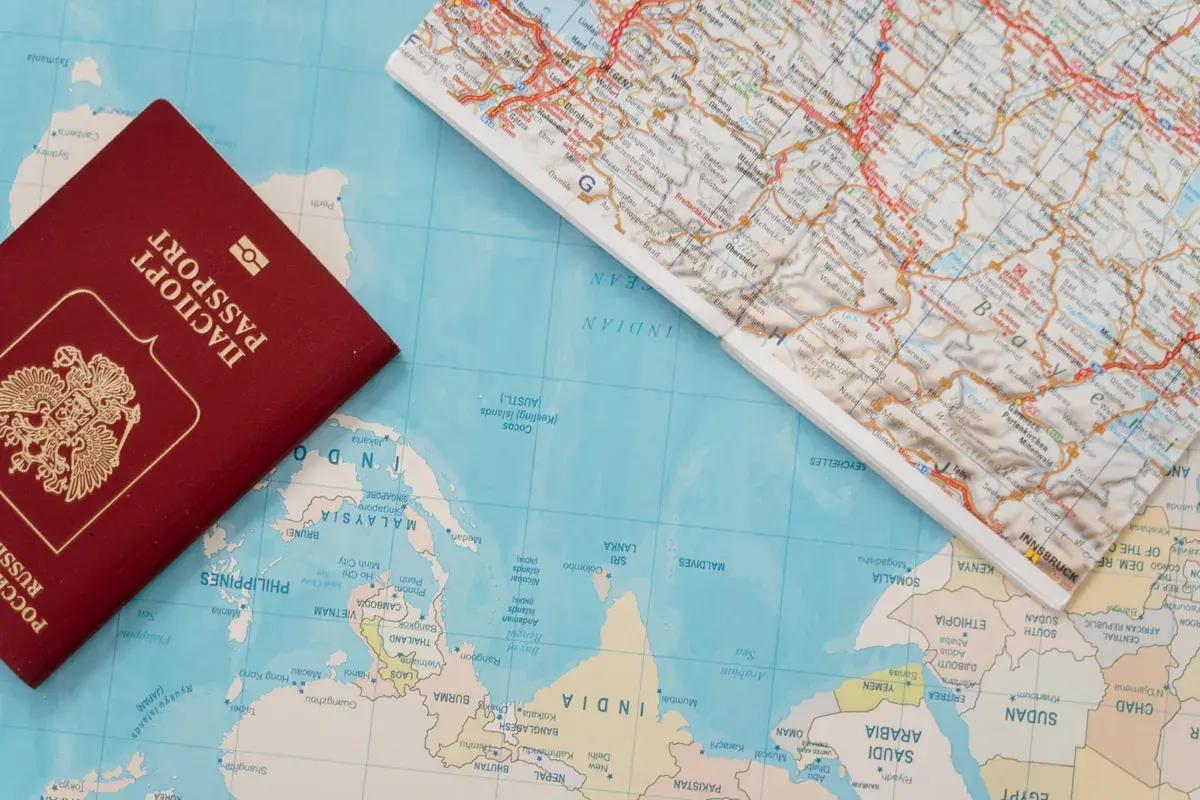 A passport resting on a paper world map beside a small notebook